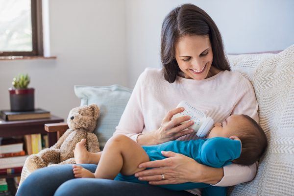 Mother holding and feeding baby from milk bottle